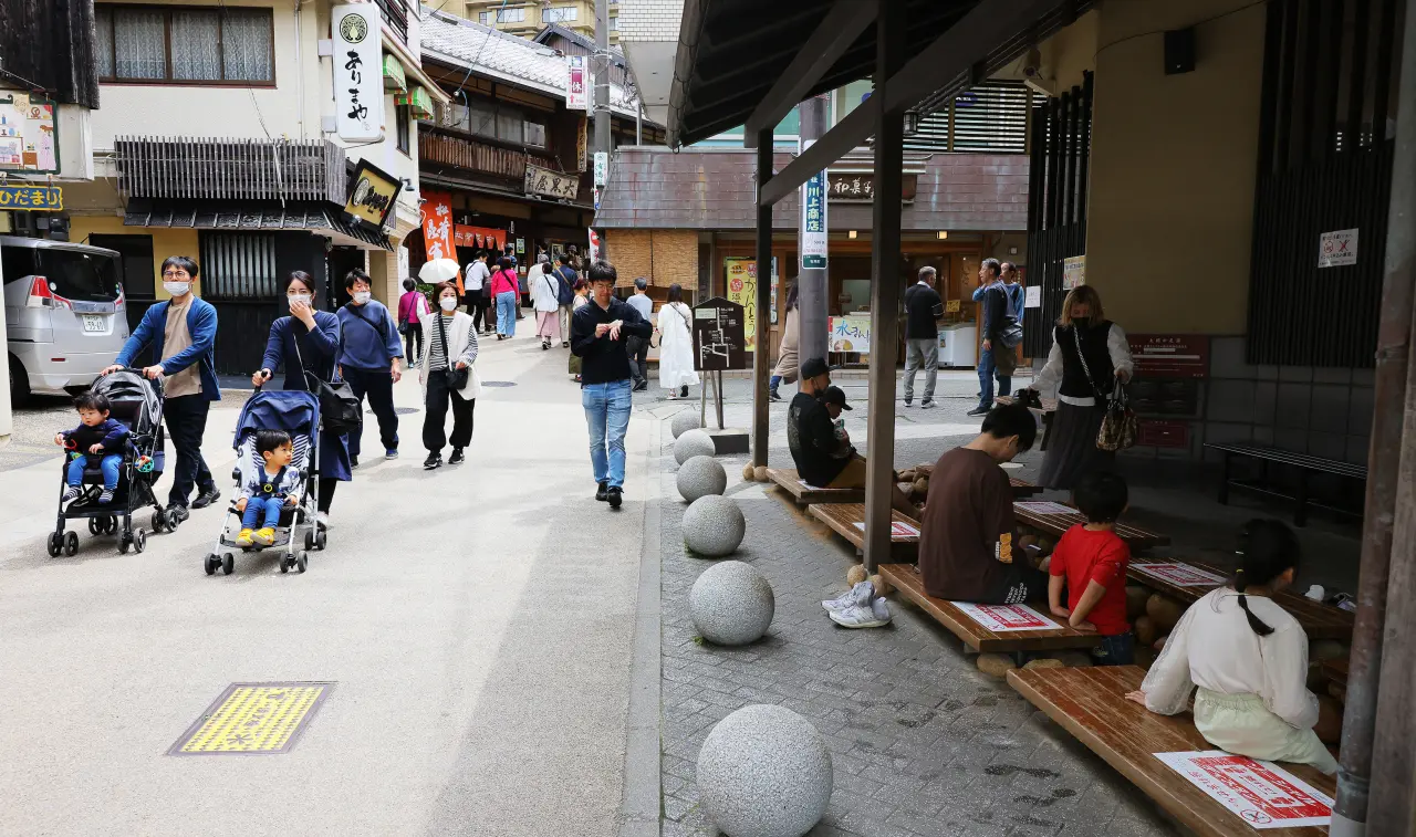 日本人改變黃金周出遊模式,只預訂溫泉旅館的住宿,不訂含晚餐的方案。圖為兵庫縣神戶市有馬溫泉區2023年4月29日黃金周第一天的景象,有遊客在溫泉街享受足湯(右)設施。法新社