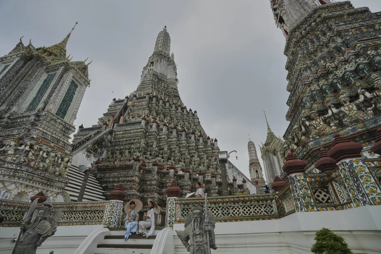 體驗泰國傳統服飾的旅客,5月15日在曼谷地標「鄭王廟」(Wat Arun、又稱黎明寺)拍照留影。美聯社