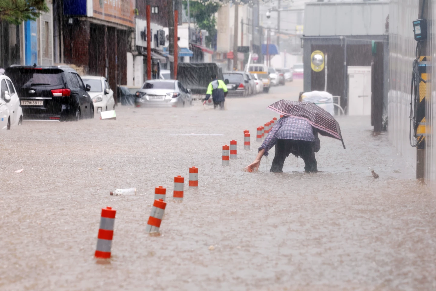 南韓光州17日雨量驚人,多地傳出水患,1名老婦撐傘涉水而行。美聯社