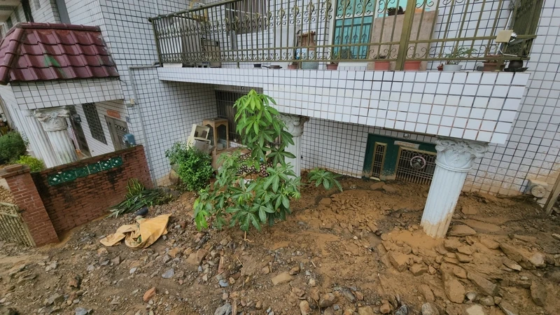 埔里鎮21日一陣強降雨,蜈蚣里7戶民宅遭土石流影響,連夜緊急安置11人;鎮公所22日派廠商機具協助受災戶清理環境。(埔里鎮公所提供)中央社