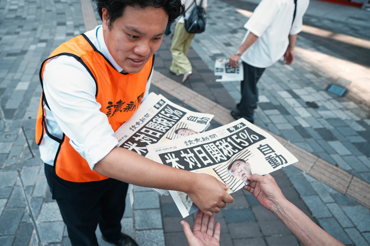 美日關稅協議出爐後,日本《讀賣新聞》人員7月23日在東京街頭發送快報。美聯社