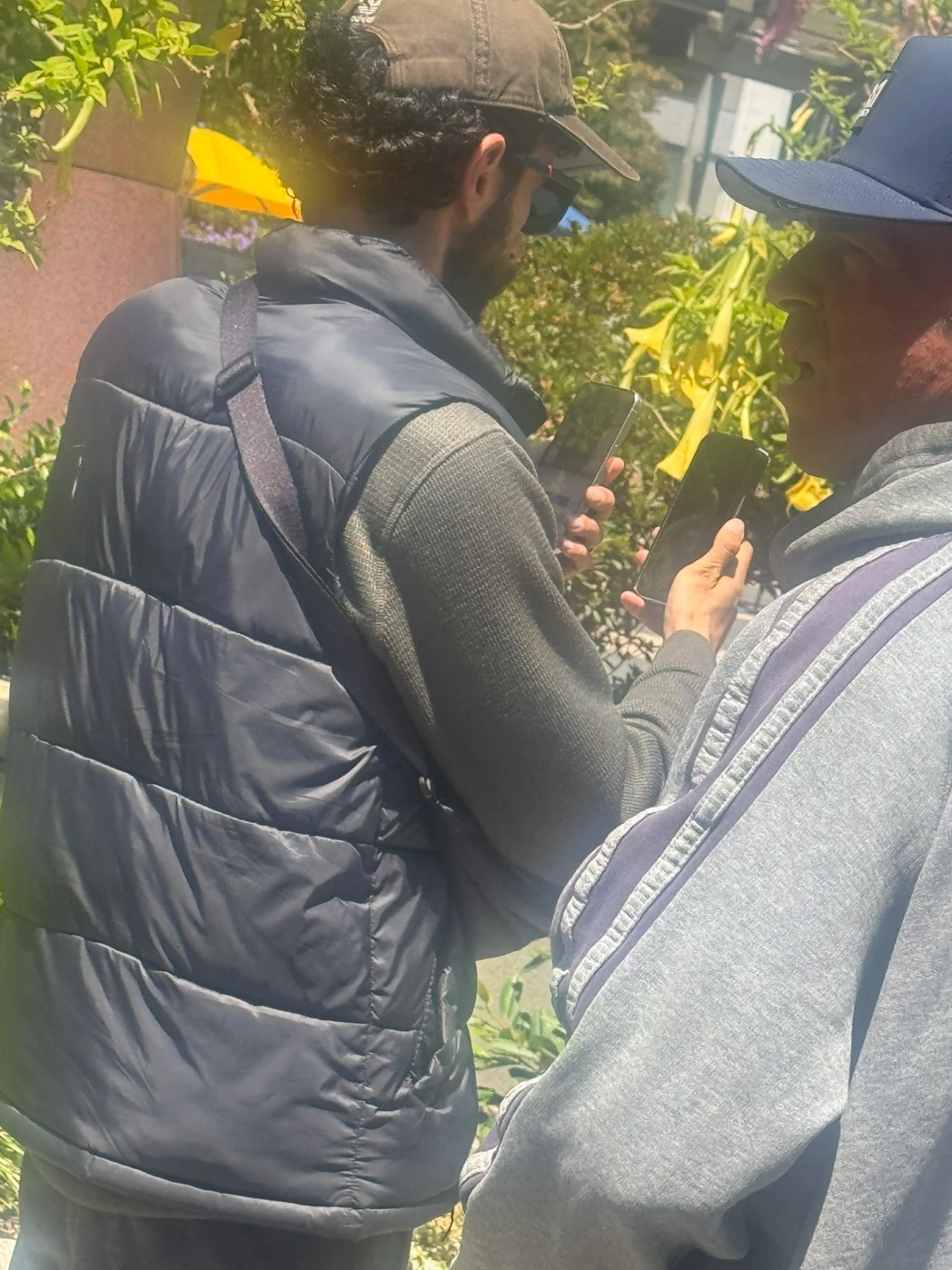 網友聲稱右邊那人是保全,想擋住iPhone 17 Pro(右手)避免被拍。翻攝自@Skyfops的X