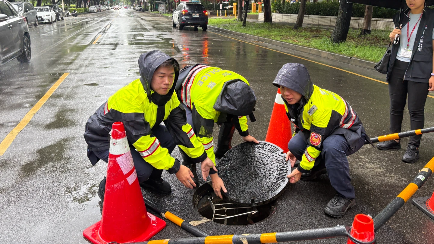 台中南屯道路人孔蓋浮起,警員合力將人孔蓋復位。警方提供
