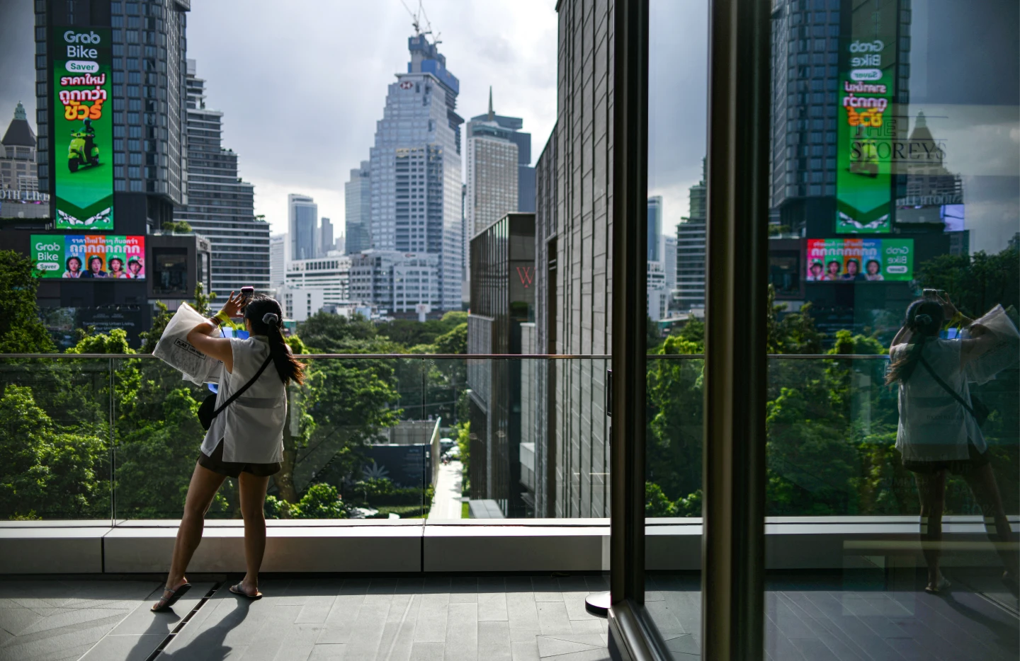 一名女子7月31日在曼谷「One Bangkok」商場,拍攝城市天際線。法新社