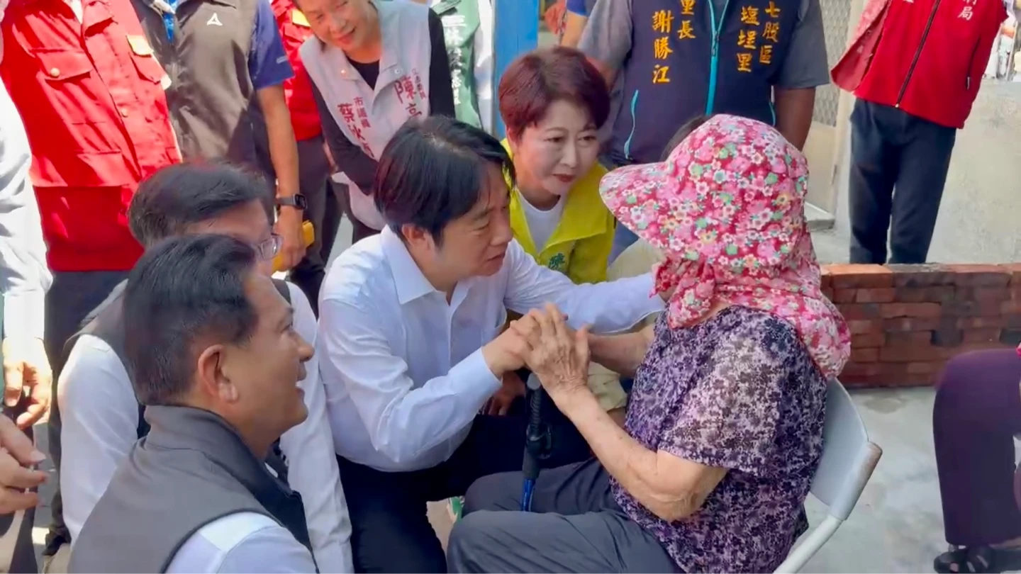 賴清德蹲下輕握婦人的手,安撫不安。民眾提供