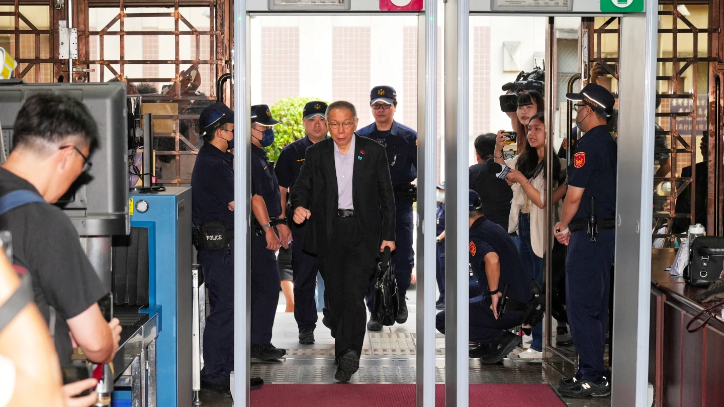 柯文哲今穿西裝出庭,衣領別著「KP」及國旗胸章。葉志明攝