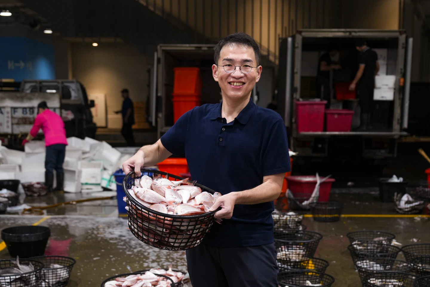 前鎮漁港的凌晨滿是拍賣的喧鬧,高雄區漁會總幹事楊孟凡提起魚籃與攤商互動,拉近彼此距離。李柏毅攝