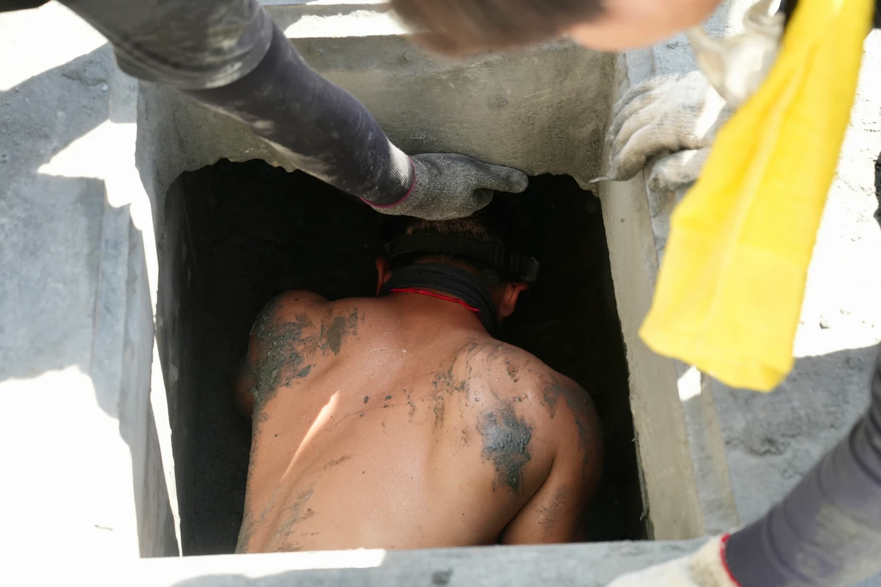 一名男性志工打赤膊整個人鑽進側溝協助清理。梁建裕攝