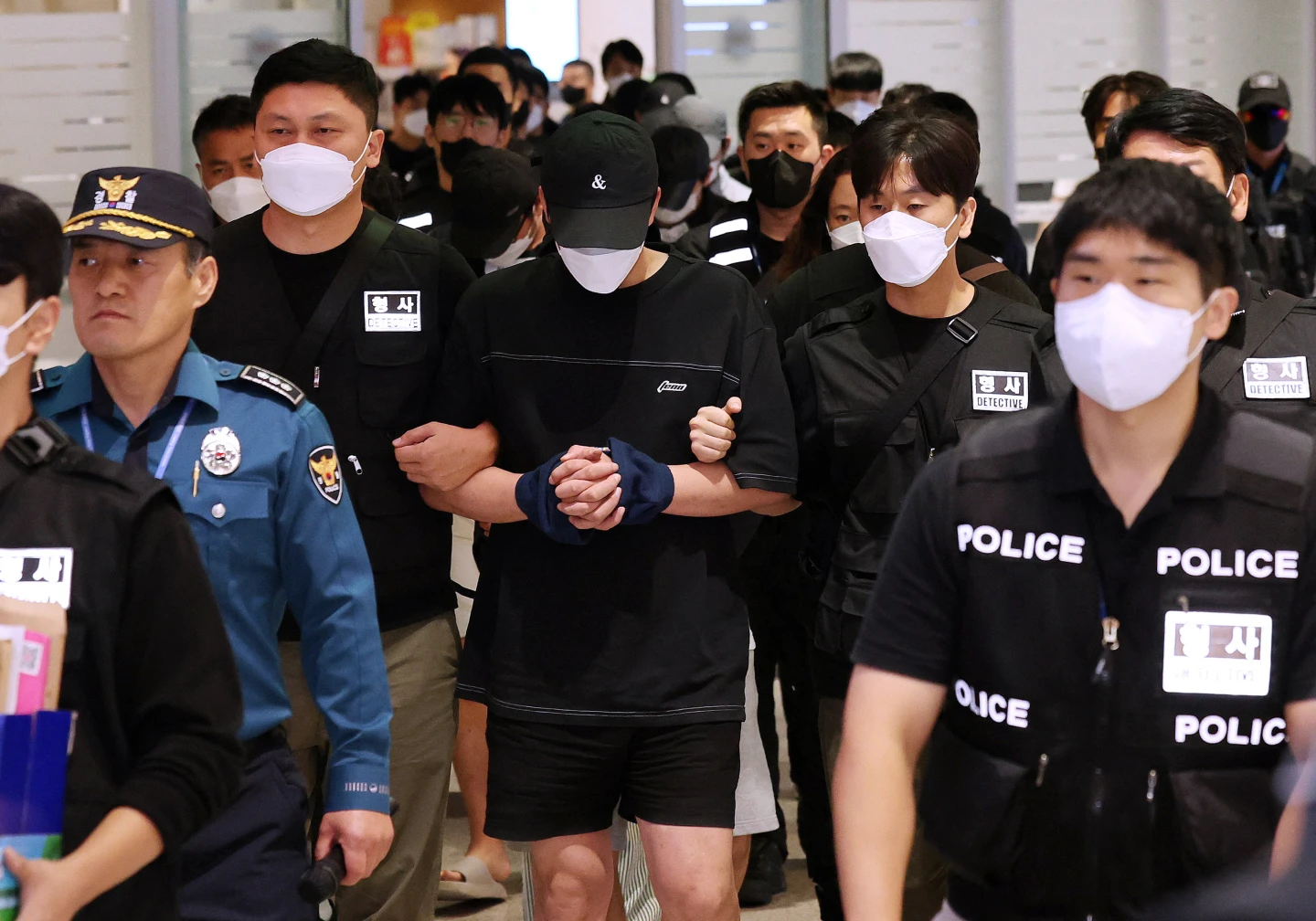 南韓18日派遣包機和190多名警察,從柬埔寨金邊載回64名詐團成員(中)法辦。法新社