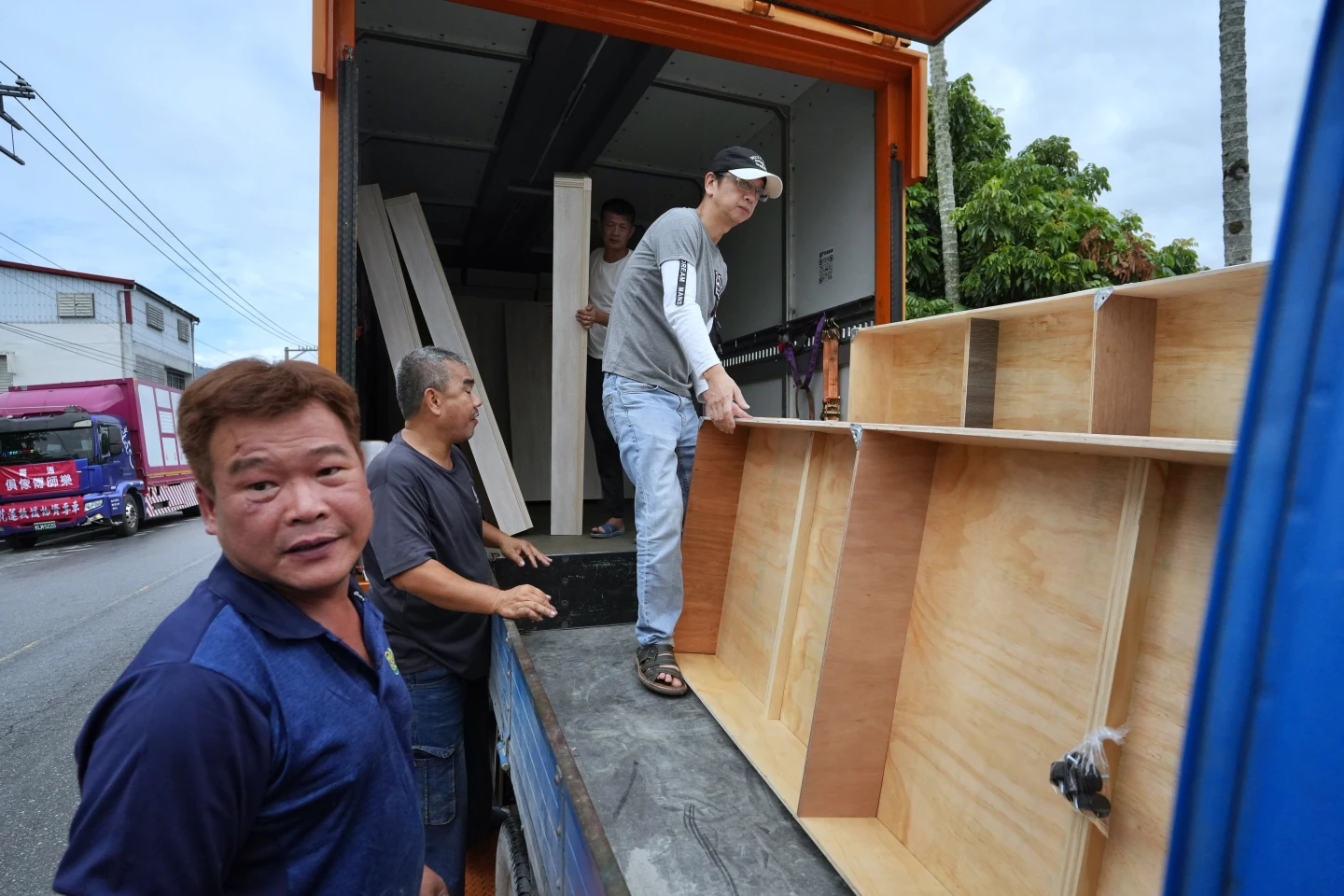 志工們攜手合作,將大型床架從貨車裝卸到發財車,準備前往災民家中。林林攝