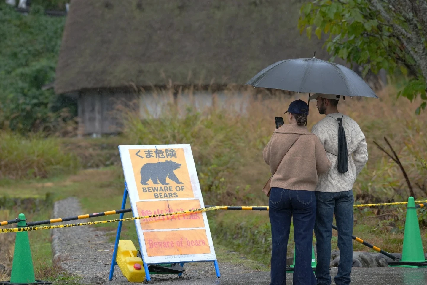2名外國遊客10月26日在岐阜縣白川鄉合掌村,研究因熊出沒封閉步道的告示。法新社